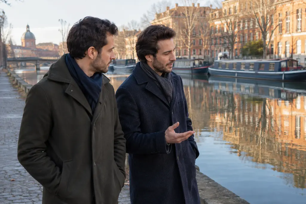 Deux frères discutent en marchant le long d’un canal bordé de façades toulousaines.