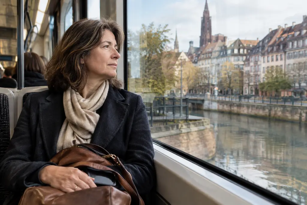 Une femme observe les façades de Strasbourg depuis la fenêtre d’un tramway.